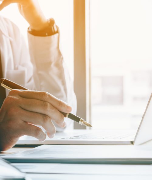 Stress businessman at office room holding pen pointing summary report graph and analyze with using laptop for searching information data.